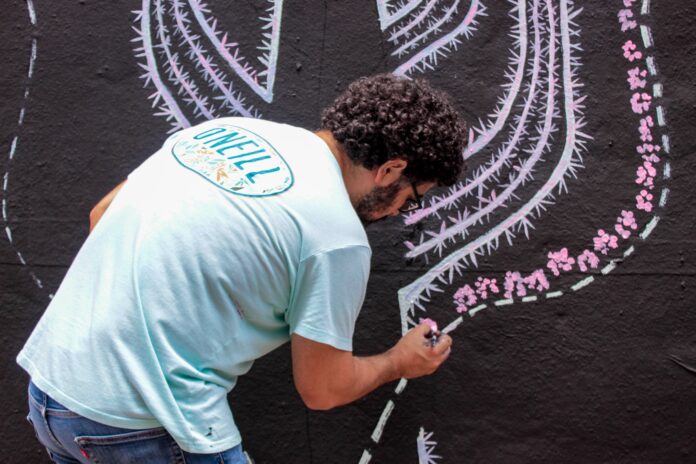 Artist painting an environmental mural in Callej&oacute;n R&iacute;o Bravo